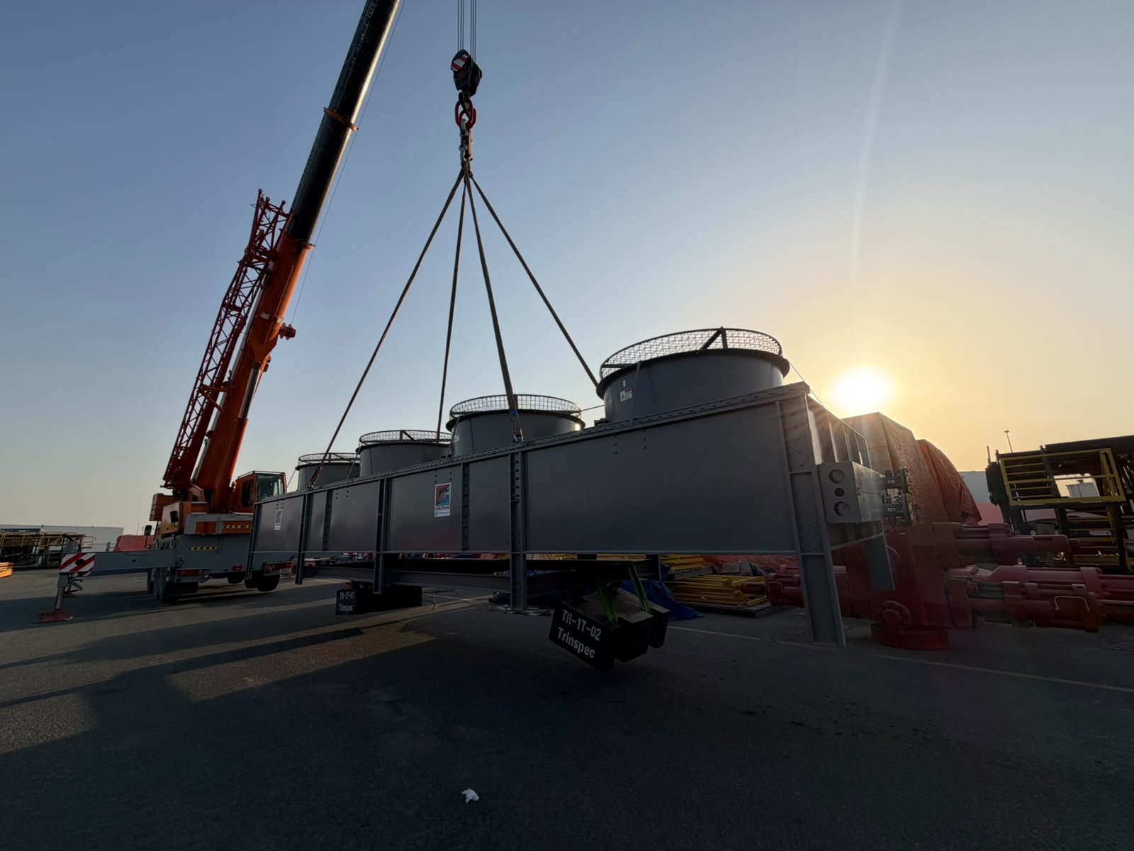 Mobile crane rigging and lifting a large capacity load at sunset